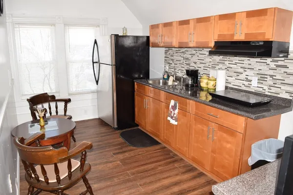 a kitchen with stainless steel appliances granite countertop a refrigerator a stove a sink a dining table and chairs with wooden floor