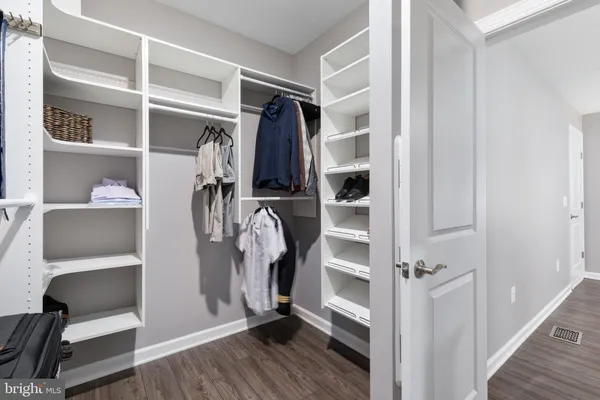 a view of walk in closet with clothes and shoes