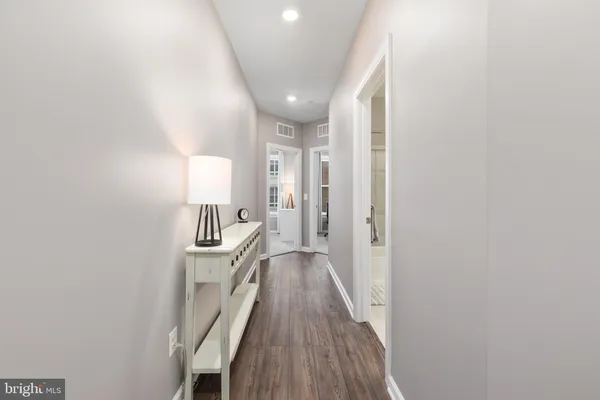 a view of a hallway with wooden floor and cabinets