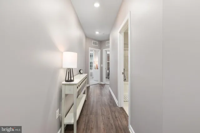 a view of a hallway with wooden floor and cabinets