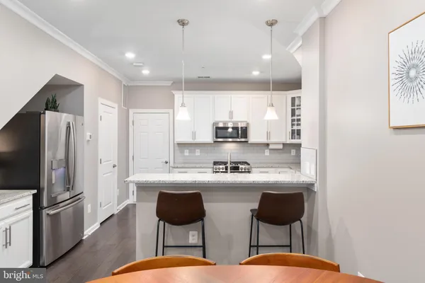 a kitchen with stainless steel appliances kitchen island granite countertop a sink a refrigerator and chairs