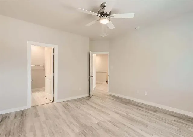 a kitchen with stainless steel appliances a stove a refrigerator a sink and white cabinets with wooden floor