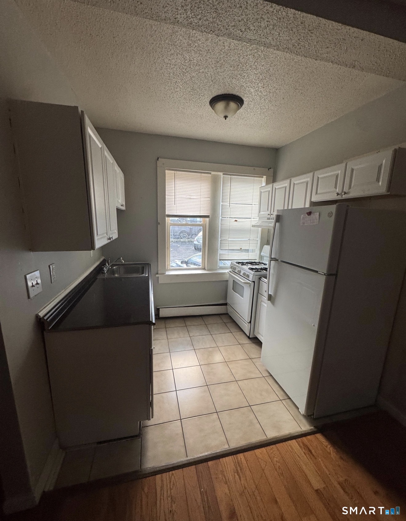 335 Wells Street, Unit 3 Bridgeport, CT 06606 - Photo 3 of 3 a kitchen with stainless steel appliances a refrigerator sink and wooden cabinets