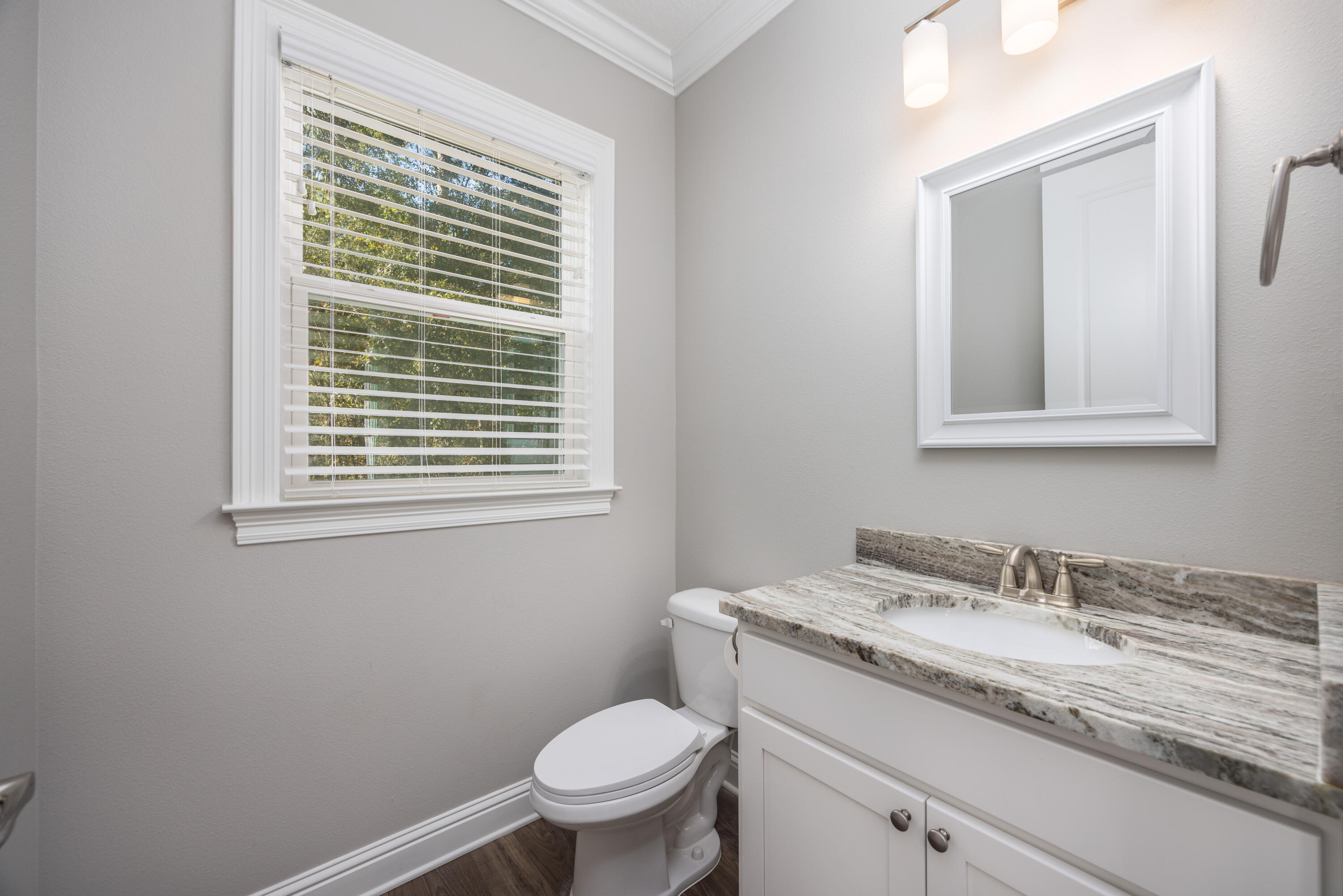 134 Laurel Oaks Drive Freeport, FL 32439 - Photo 15 of 30 a bathroom with a granite countertop toilet a sink a mirror and a window