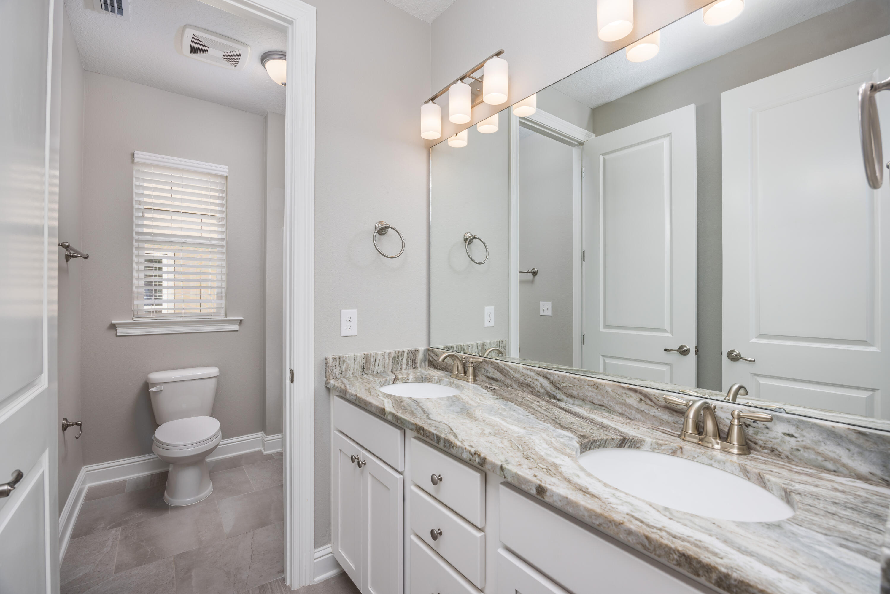 134 Laurel Oaks Drive Freeport, FL 32439 - Photo 26 of 30 a bathroom with a granite countertop double vanity sink a mirror and a toilet