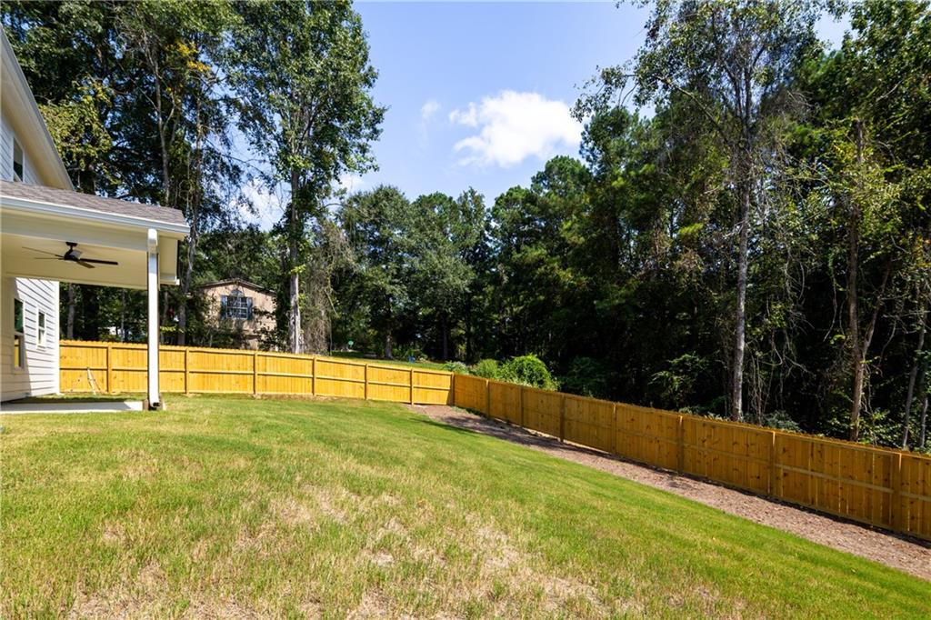 111 Lee Road Phenix City, AL 36867 - Photo 4 of 23 Expansive backyard with a new wood privacy fence, covered patio featuring a ceiling fan, and lush green lawn