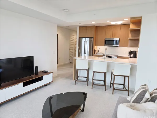 a living room with furniture a flat screen tv and kitchen view