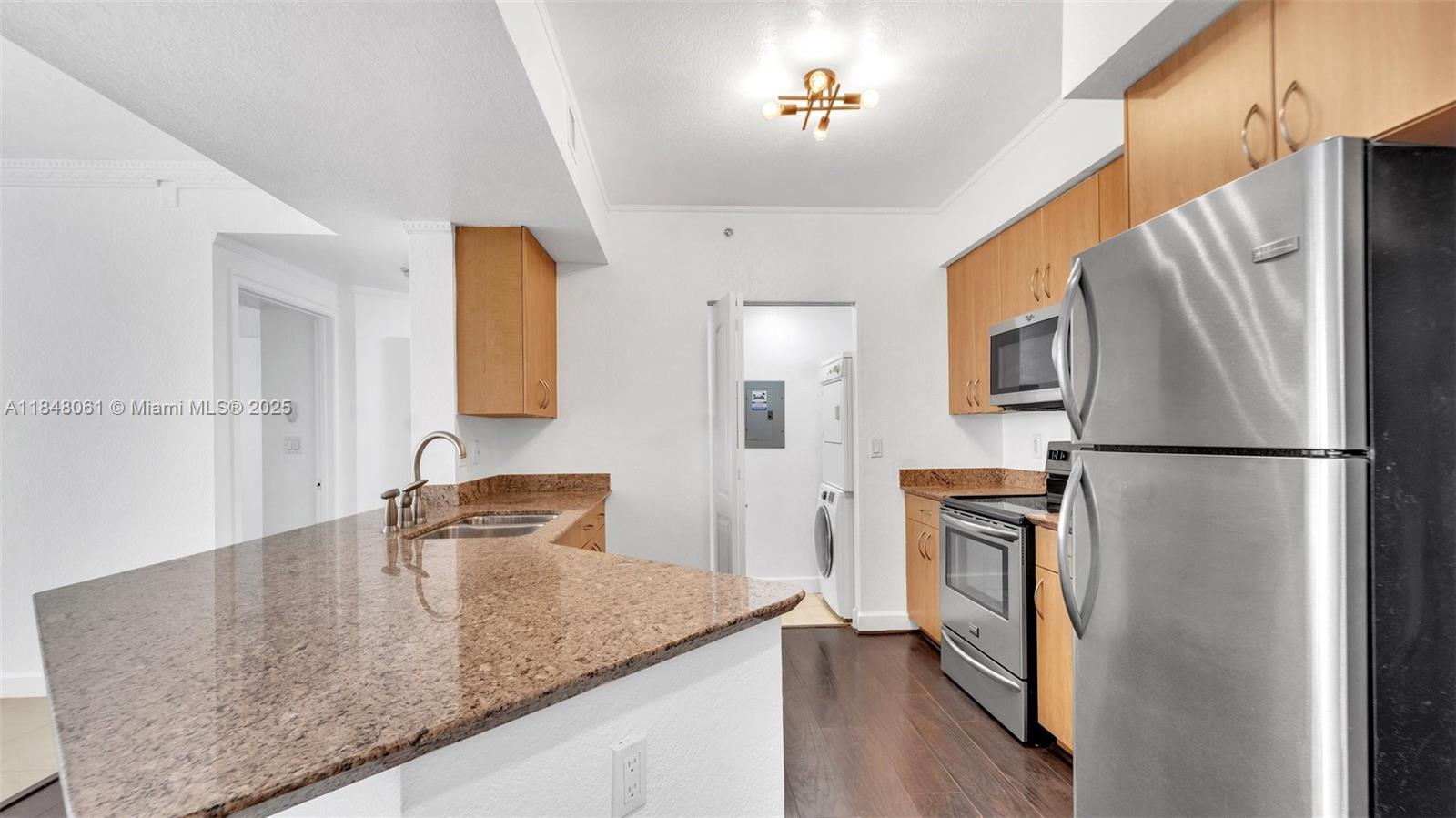 a kitchen with stainless steel appliances granite countertop a refrigerator a stove and a sink with wooden floor