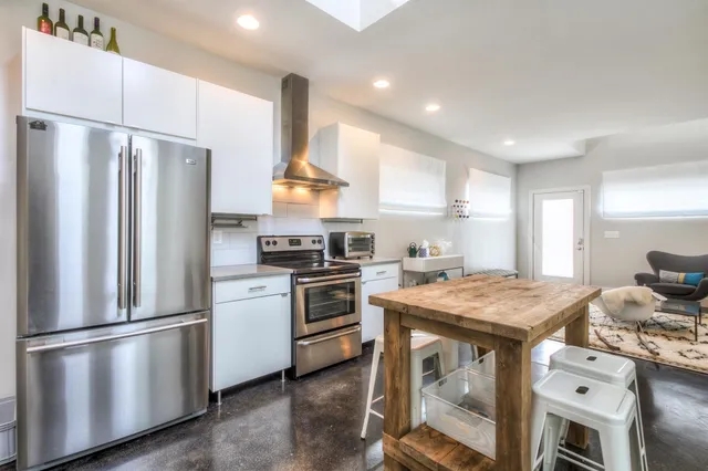 a kitchen with stainless steel appliances granite countertop a refrigerator a stove a sink cabinets and a refrigerator