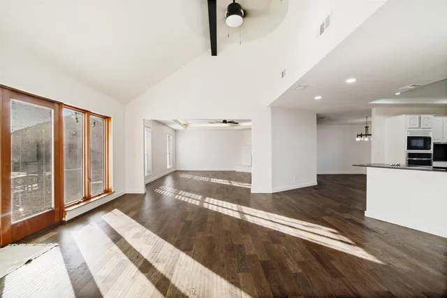 an empty room with chandelier fan and windows