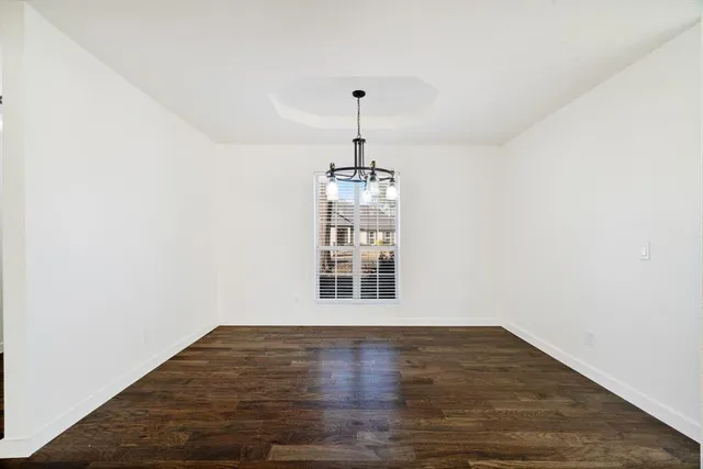 a view of empty room with wooden floor and window