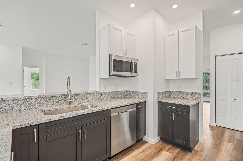 8001 Leonardo Street Sebring, FL 33872 - Photo 13 of 32 a kitchen with stainless steel appliances granite countertop a stove a sink and a microwave