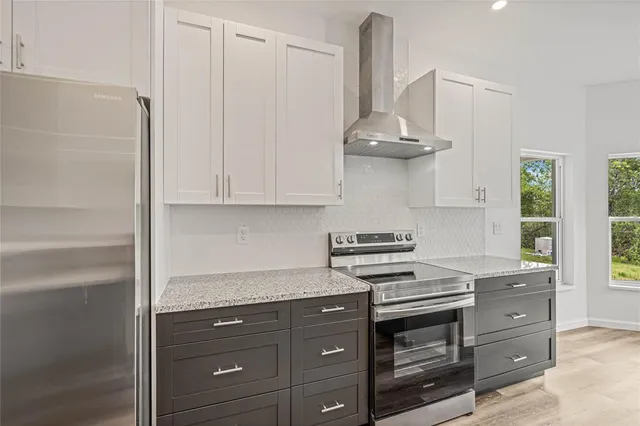 a kitchen with stainless steel appliances granite countertop a stove and a white cabinet