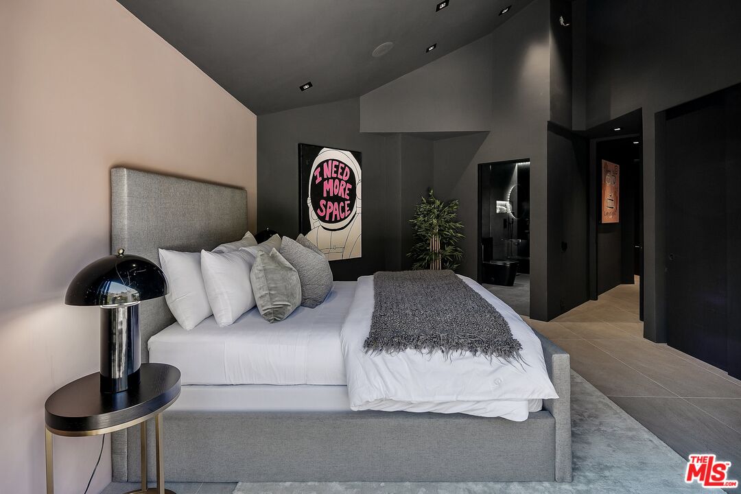 2001 Roscomare Road Los Angeles, CA 90077 - Photo 22 of 62 a bedroom with a bed and a table with potted plants