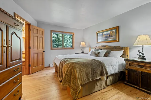 a spacious bedroom with a bed and wooden floor