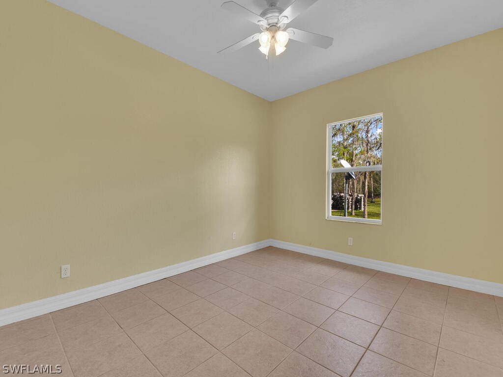 20401 Carter Road Estero, FL 33928 - Photo 23 of 42 en empty room with windows and chandelier fan