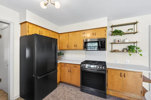 a kitchen with stainless steel appliances granite countertop a refrigerator a stove and a sink with wooden floor