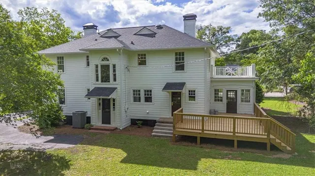 a view of a white house with a wooden deck and a backyard