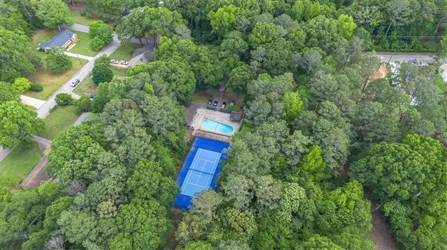 an aerial view of a house with outdoor space and trees all around