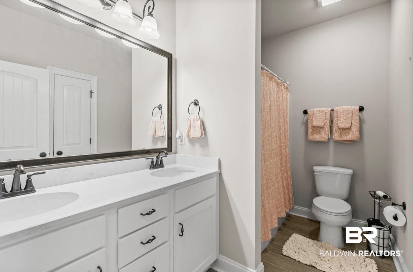 10126 Chipper Lane Foley, AL 36535 - Photo 22 of 30 Full bathroom with double vanity, a shower with shower curtain, and dark wood-style flooring