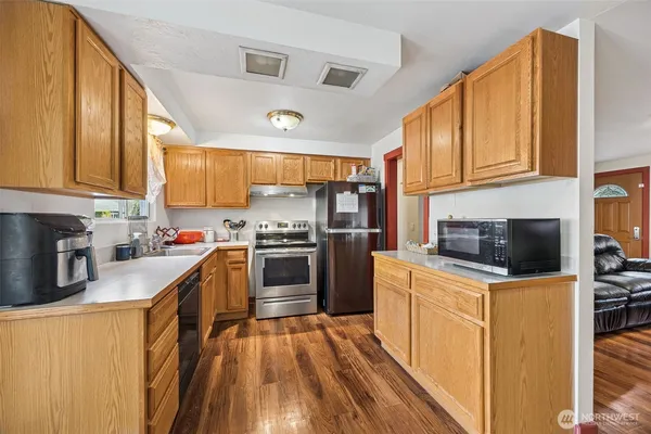 a kitchen with stainless steel appliances a stove a sink dishwasher a refrigerator and cabinets with wooden floor