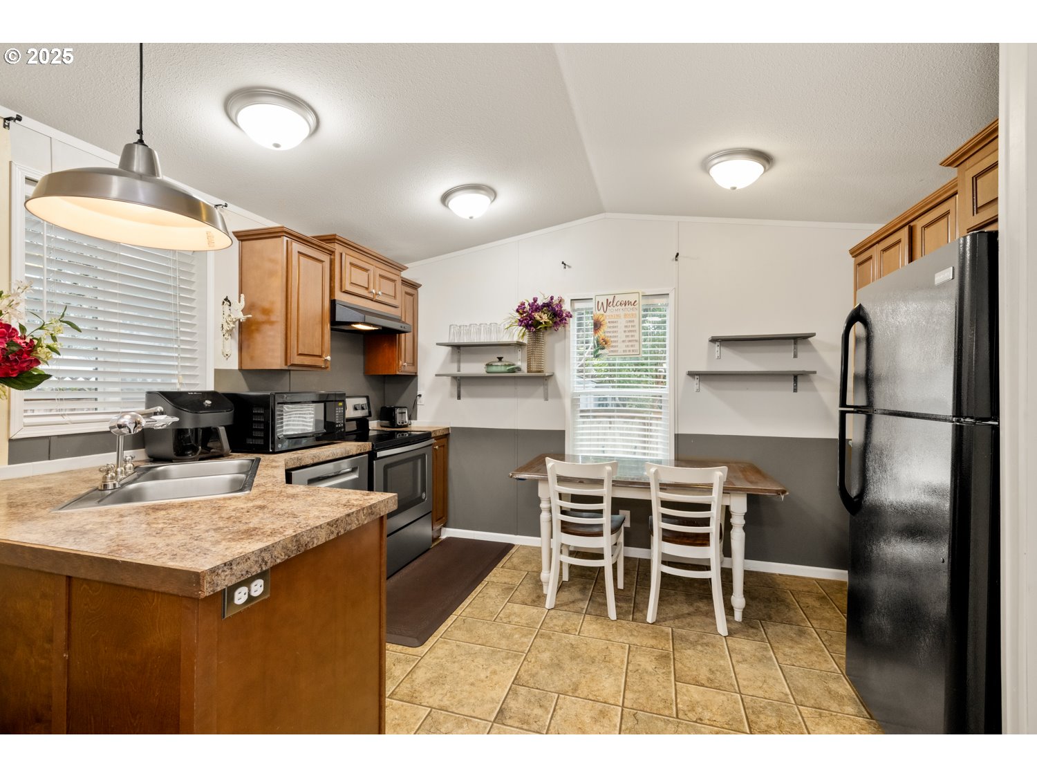 2696 Southeast Palmquist Road Gresham, OR 97080 - Photo 6 of 21 a kitchen with a refrigerator a stove a sink and a dining table with wooden floor