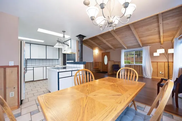a kitchen with stainless steel appliances kitchen island granite countertop a table chairs in it and wooden floors
