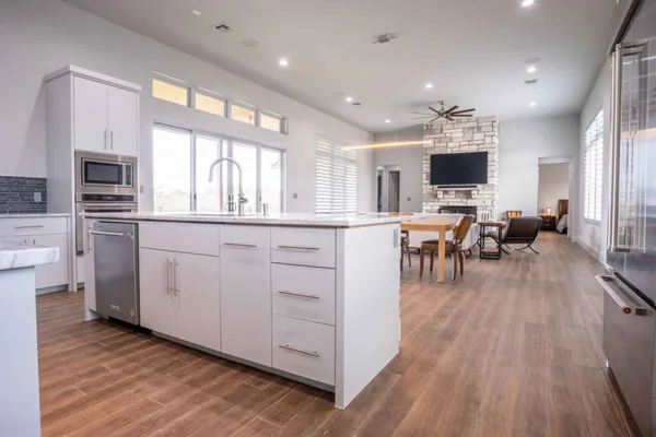 a living room with stainless steel appliances granite countertop furniture wooden floor and a view of kitchen