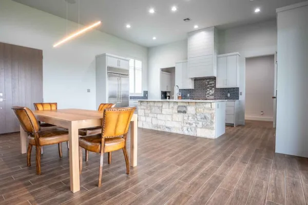 a kitchen with stainless steel appliances kitchen island granite countertop wooden floors and white cabinets