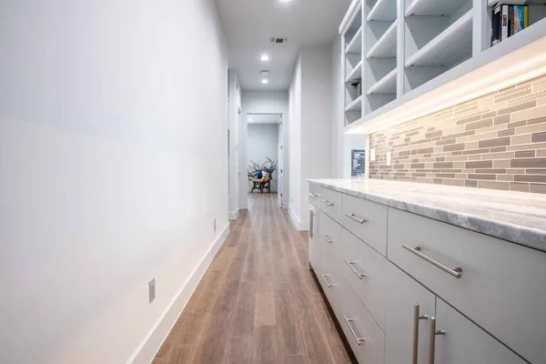 a hallway with white cabinets and wooden floor