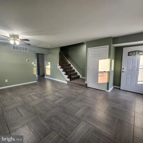 a view of an empty room with stairs and chandelier fan
