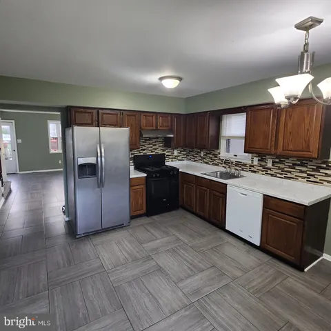 a kitchen with stainless steel appliances granite countertop a stove a sink dishwasher a refrigerator and a oven with wooden cabinets