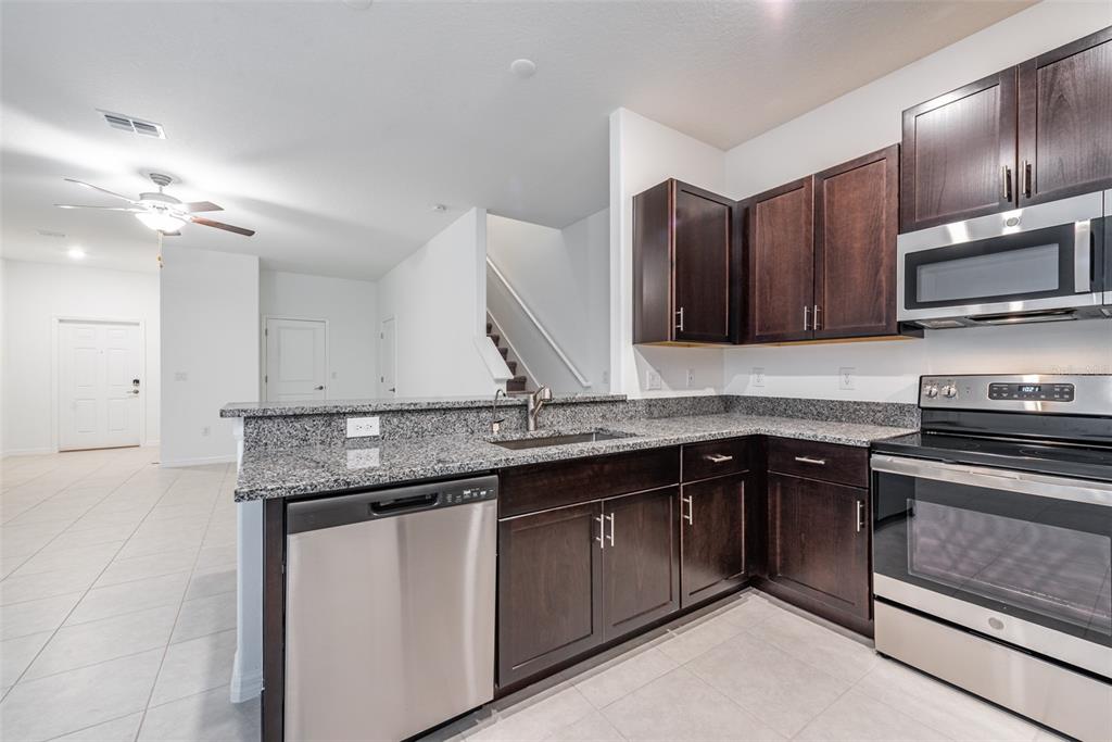 14348 Editors Note Street Ruskin, FL 33573 - Photo 3 of 29 a kitchen with a sink and a stove top oven with wooden floor