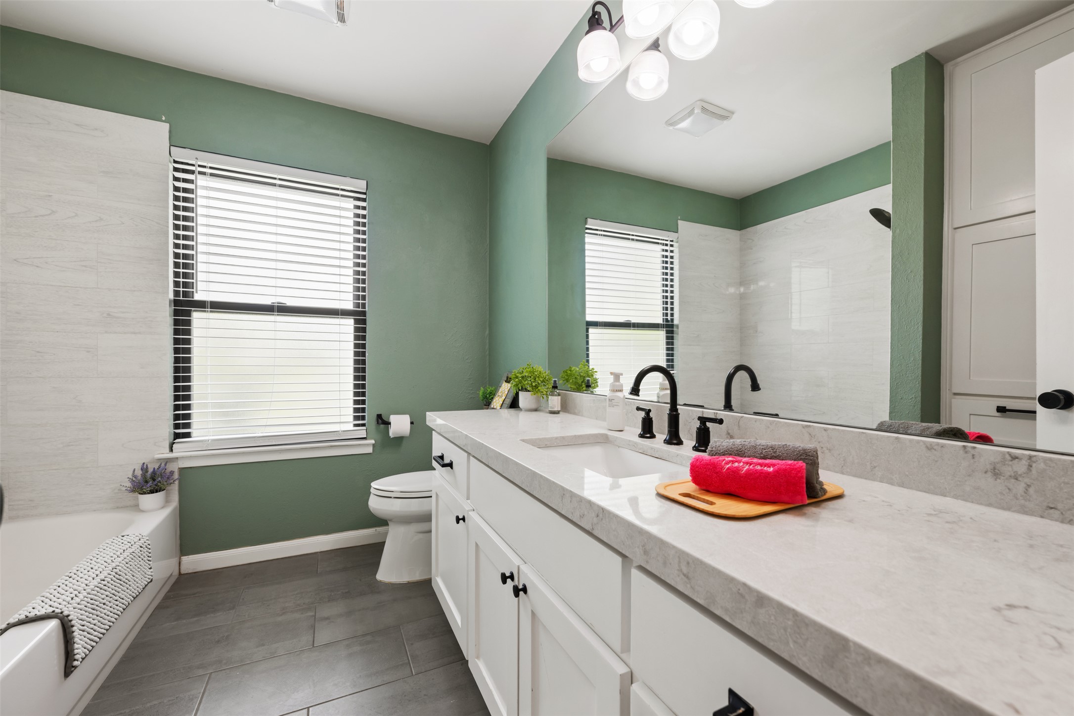 1600 Pin Oak Lane Round Rock, TX 78681 - Photo 30 of 40 Bathroom featuring a dual vanity with a light-toned countertop, white cabinetry, matte black fixtures, and a large mirror