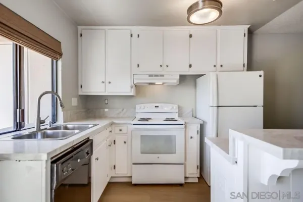 a white kitchen with sink and white stainless steel appliances