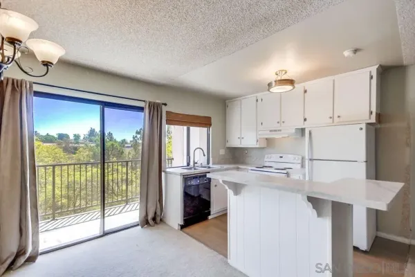 a kitchen with kitchen island a stove a sink a refrigerator and a view of living room