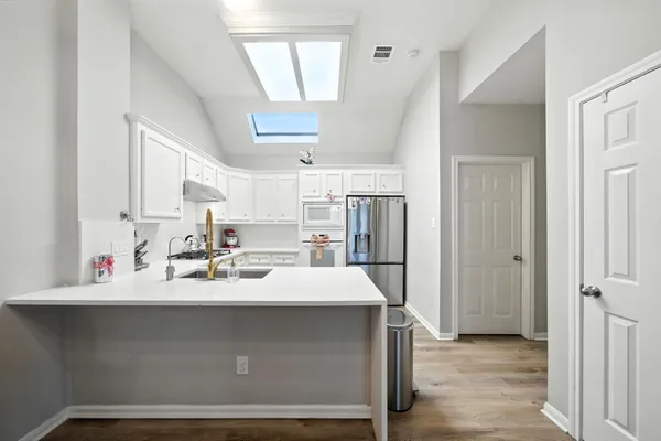 a kitchen with kitchen island a sink appliances and cabinets