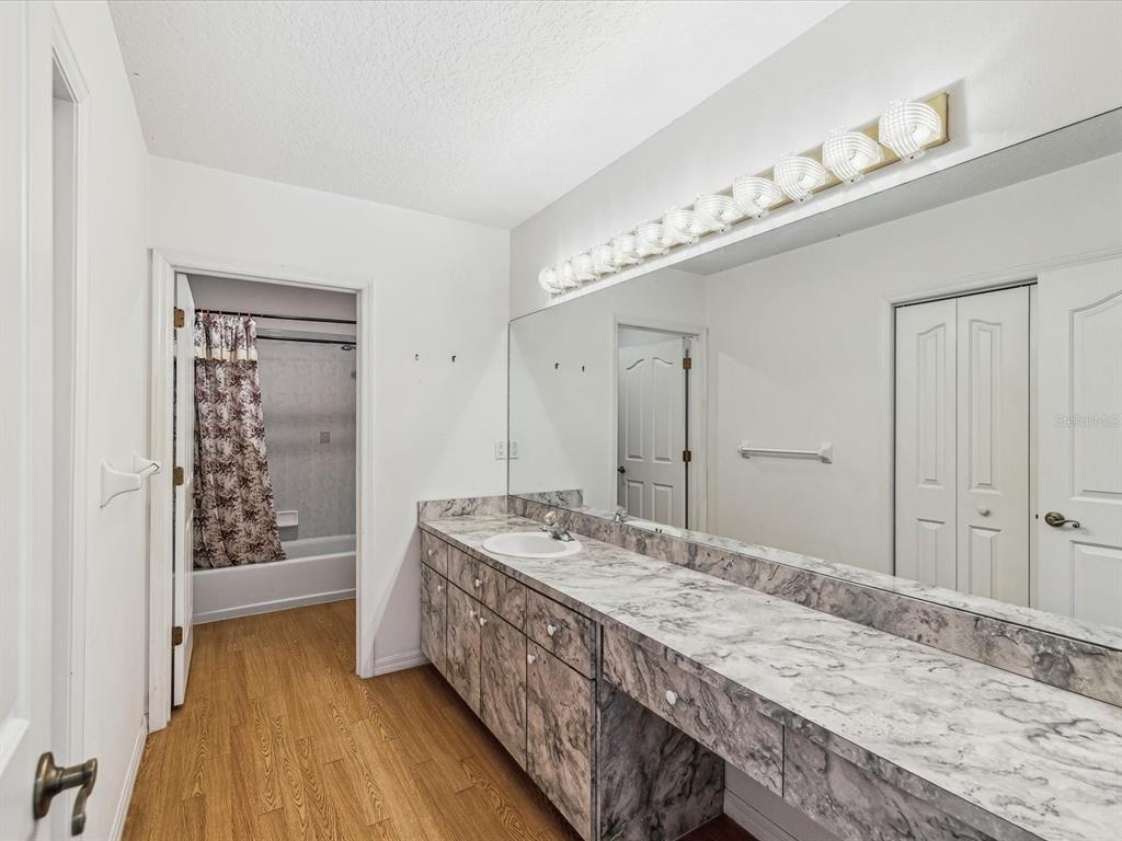15420 Aubrey Avenue Spring Hill, FL 34610 - Photo 22 of 28 a bathroom with a granite countertop sink a large mirror and shower