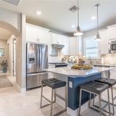 a kitchen with stainless steel appliances granite countertop a refrigerator a stove a sink a dining table and chairs with wooden floor