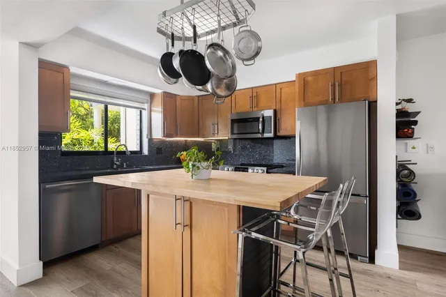 a kitchen with stainless steel appliances a table chairs refrigerator and microwave