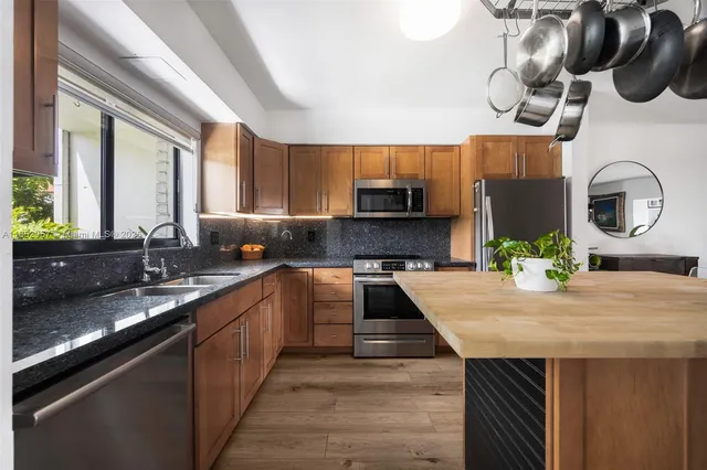 a kitchen with kitchen island granite countertop a sink a counter top space cabinets and stainless steel appliances
