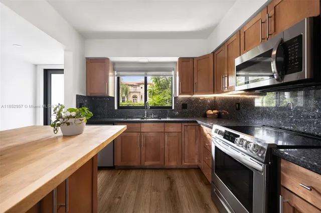 a kitchen with stainless steel appliances granite countertop a sink a stove and a microwave