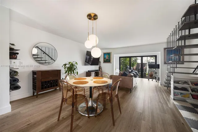 a dining room with wooden floor a chandelier a wooden table and chairs