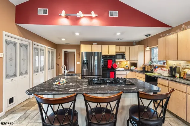 a kitchen with stainless steel appliances granite countertop a table chairs and a refrigerator