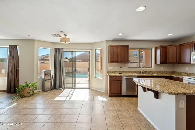 a large kitchen with granite countertop a stove top oven a sink dishwasher a dining table and chairs with wooden floor