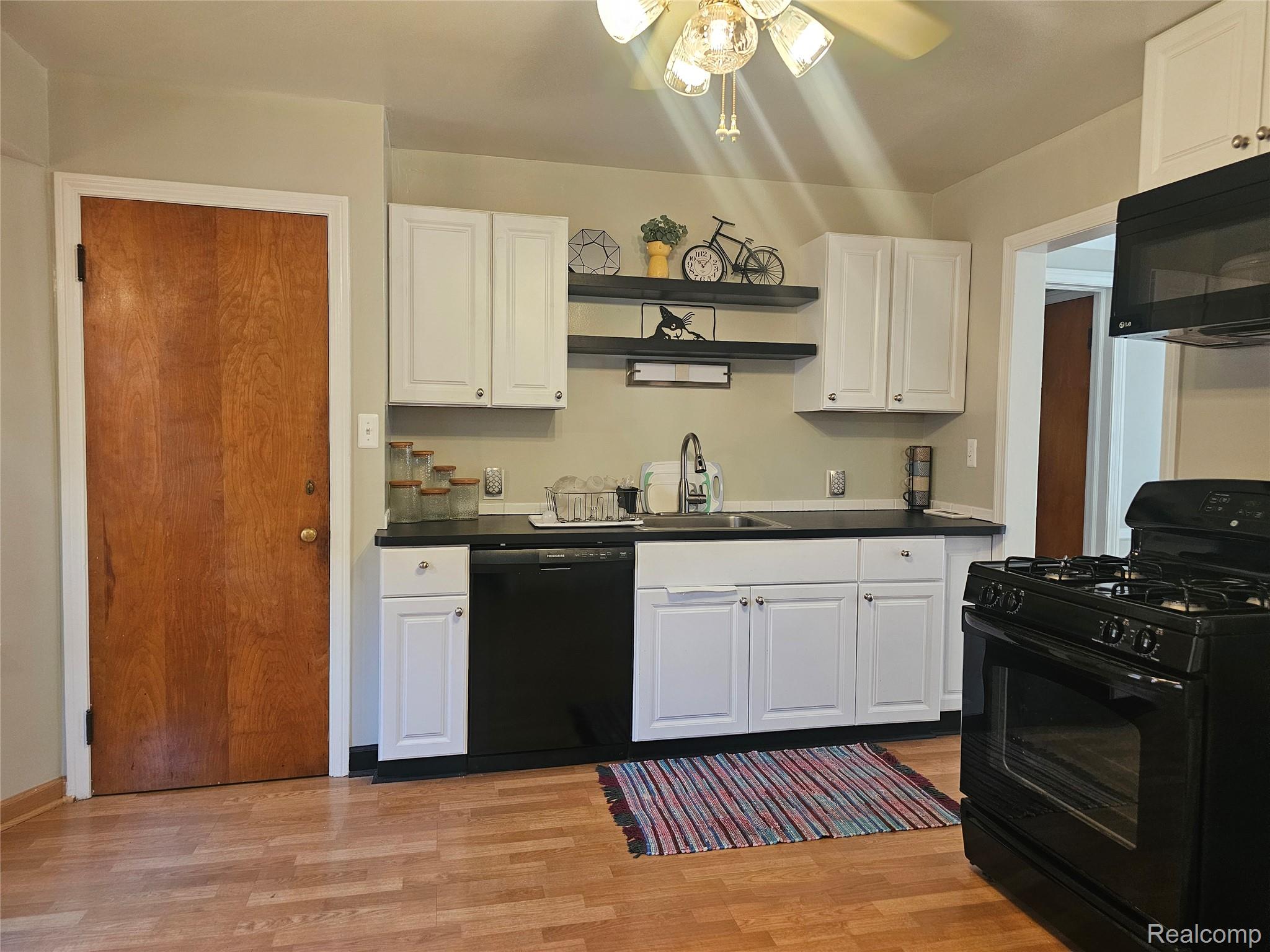 5240 Harvard Road Detroit, MI 48224 - Photo 11 of 18 Kitchen featuring white cabinetry, black countertops, a stainless steel sink, black appliances, and open shelving