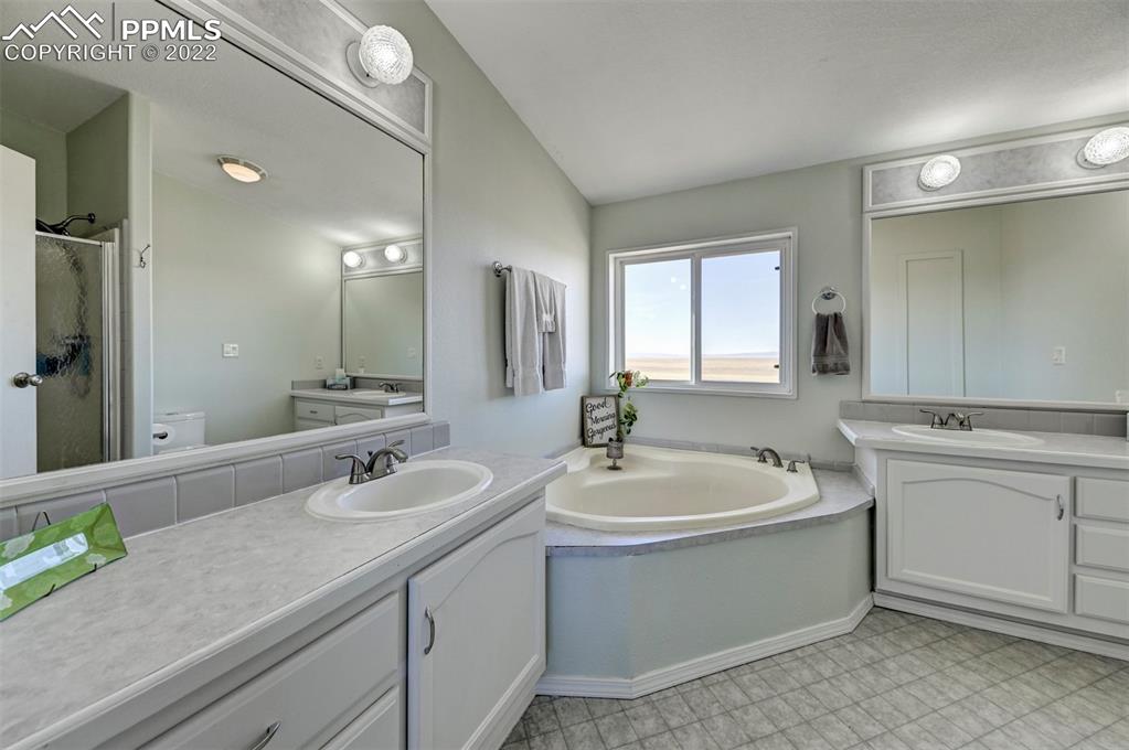 13190 South Lauppe Road Yoder, CO 80864 - Photo 24 of 38 a bathroom with a double vanity sink a mirror and a bathtub