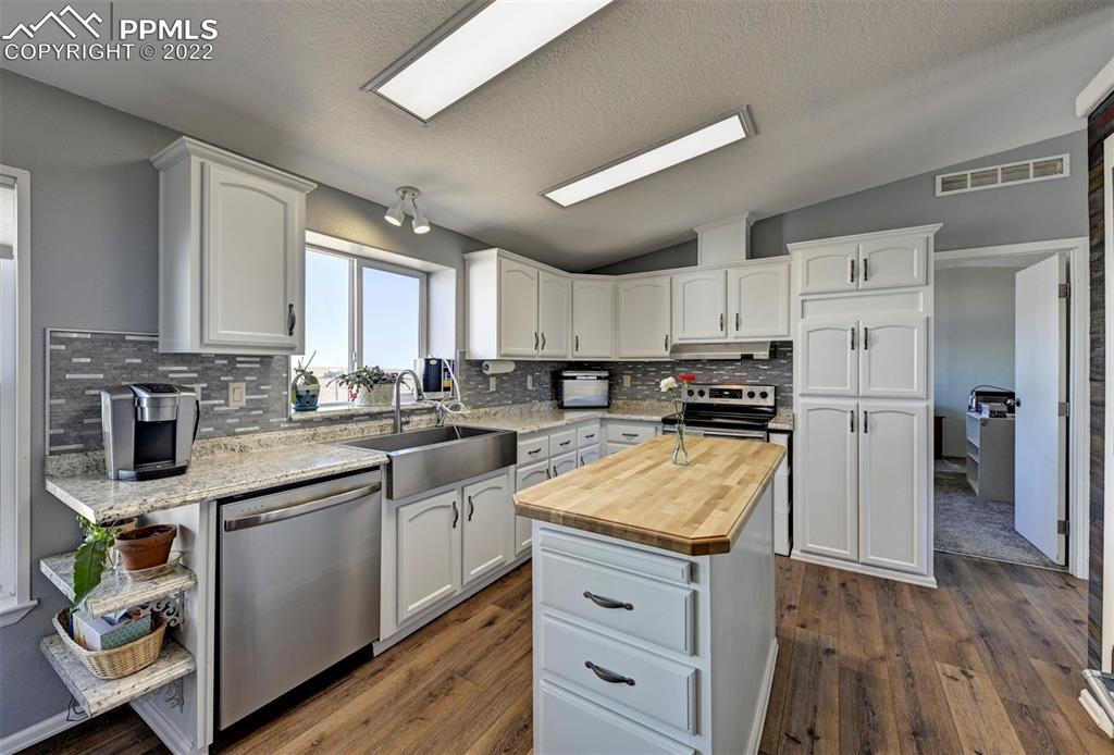 13190 South Lauppe Road Yoder, CO 80864 - Photo 7 of 38 a kitchen with granite countertop a refrigerator a sink dishwasher and white cabinets with wooden floor