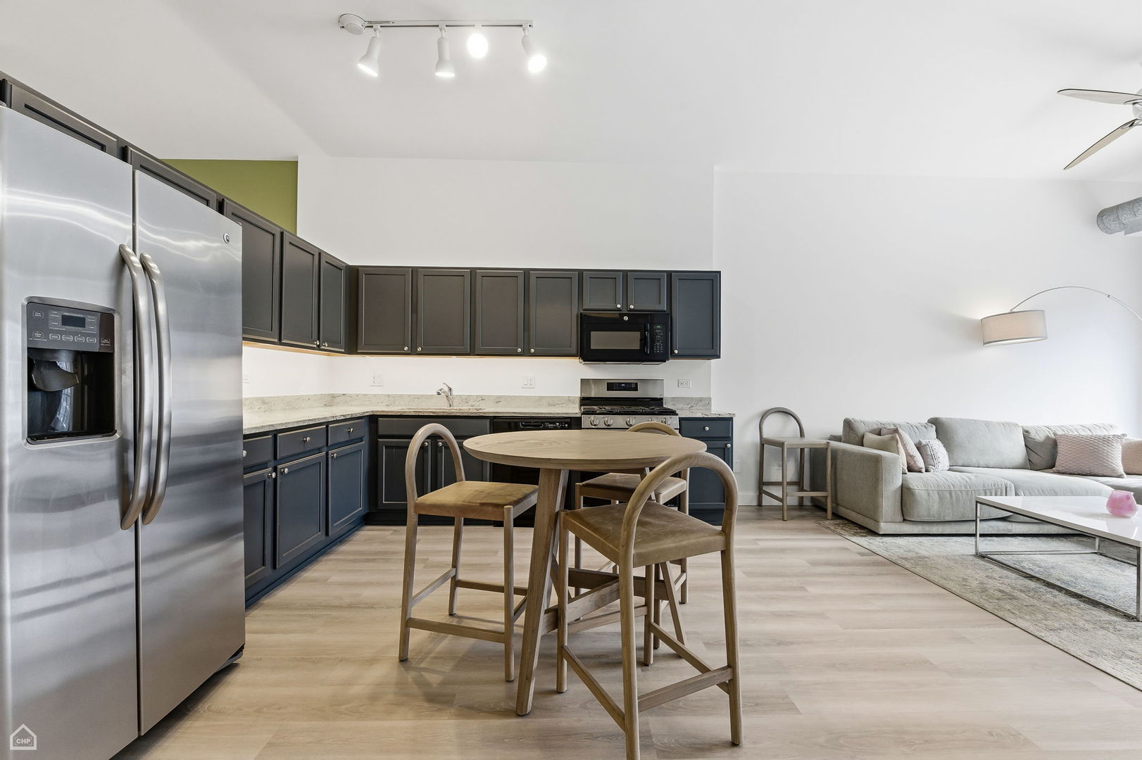 1000 East 53rd Street, Unit 215 Chicago, IL 60615 - Photo 4 of 17 a kitchen with stainless steel appliances kitchen island granite countertop a table chairs microwave and refrigerator