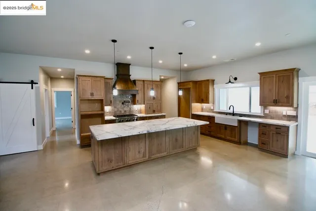 a large kitchen with kitchen island a sink stainless steel appliances and cabinets